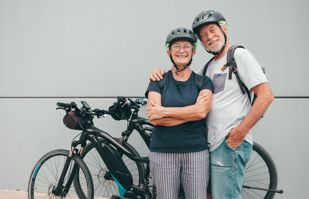 Two riders wearing helmets before riding eBikes through city traffic